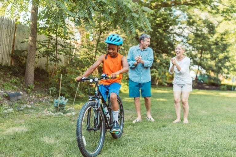 A Happy Couple Cheering For Their Son Riding A Bike